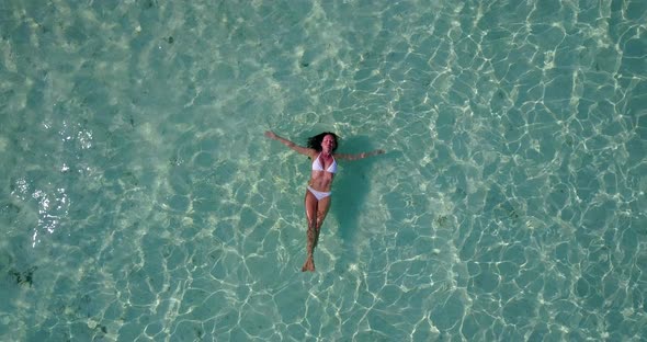 Young smiling lady on holiday by the sea at the beach on summer white sandy and blue 4K background