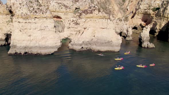 Aerial shot flying over people kayaking on the coast of Lagos in Portugal