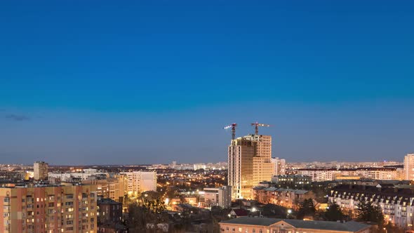 Night Cityscape and Large Tower Cranes Build Multistorey Buildings