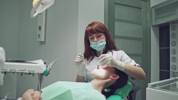 Beautiful dentist treating teeth to a woman patient in clinic