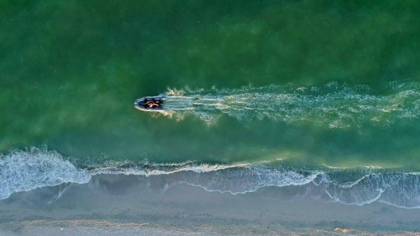 Motor boat travels at high speed along the sea shore. Aerial view. 