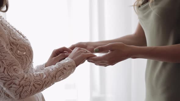 Bride Girlfriends Bridesmaid Holding Hand of Woman in Wedding Dress at Home Apartment Near Window