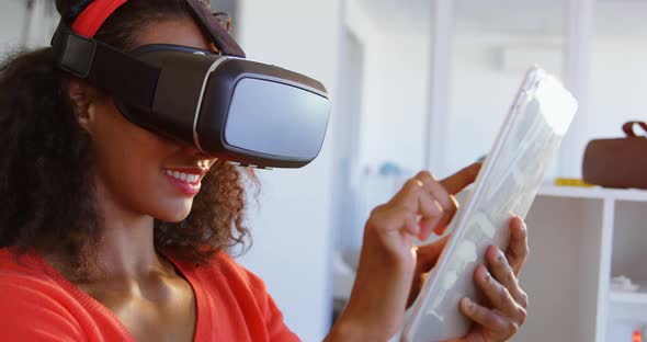 Side view of American African female fashion designer using virtual reality headset and digital tabl