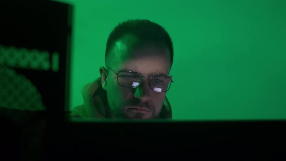 A Caucasian Man in Glasses Works on the Computer Types Checks the Information Coding Studying