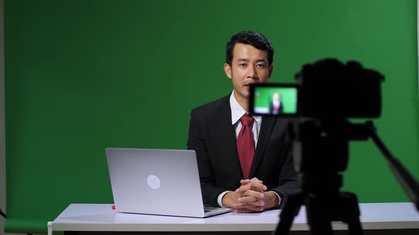 Professional Asian Male Anchor Reporting On Green Screen At Home Studio. Chroma Key