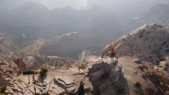 Aerial woman hiking on the edge of the San Rafael River Canyon in Utah