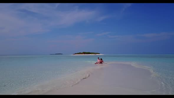 Boy and girl engaged on idyllic island beach holiday by transparent sea with white sand background o