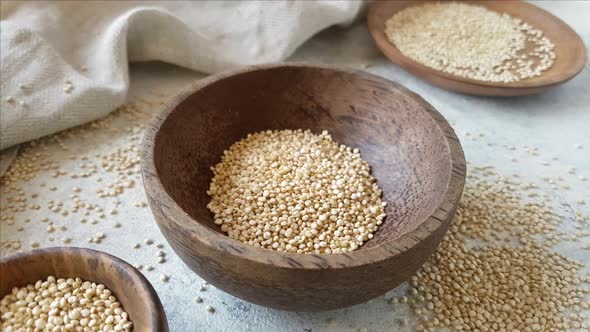 Pour Raw white Quinoa into A wooden bowl close up