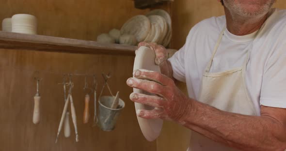 Senior caucasian man wearing apron and making pottery in his workshop