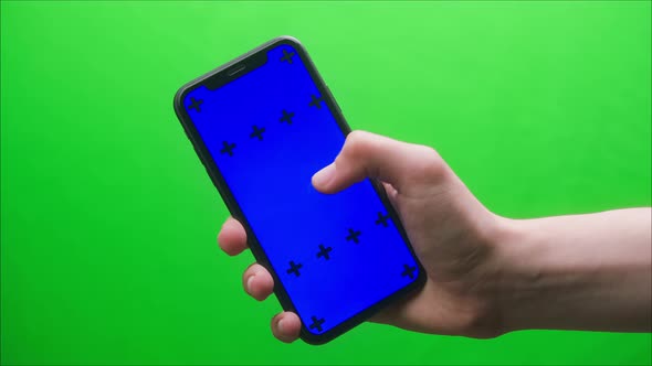 Closeup of Smartphone with Blue Screen Young Man Hands Holding Mobile Phone on Green Background