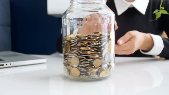 Closeup  Footage of Young Burninesswoman Throwing Coins in Glass Jar