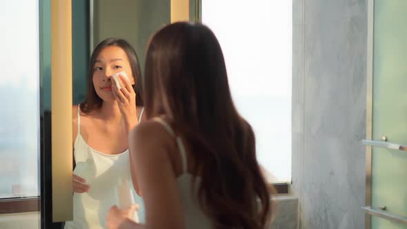 Young asian woman check her face on mirror