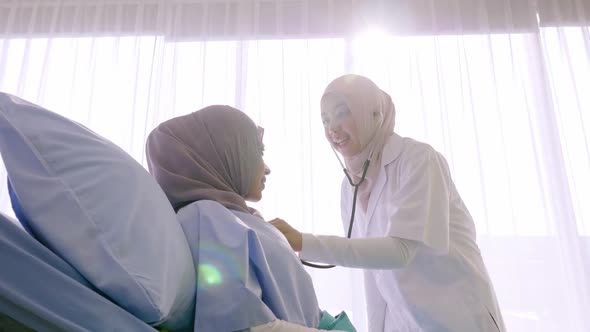 Doctor listening to patient's heart rate with stethoscope in hospital ward