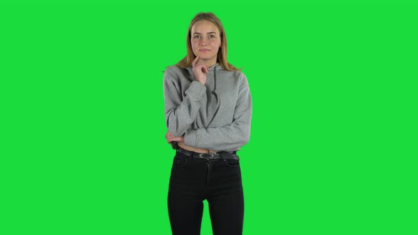 Young Woman with Blond Hair Is Looking Straight and Smiling on a Green Screen