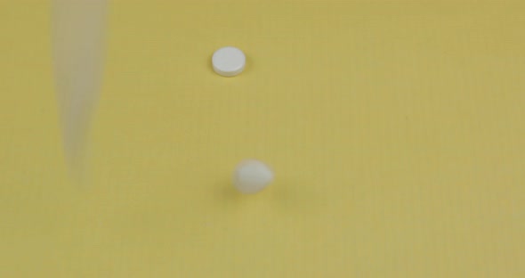 Many Pills Fall on a Yellow Surface. Round and Oval White Pills