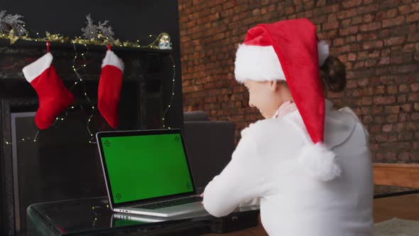 Woman in Santa hat having a video chat on laptop at home