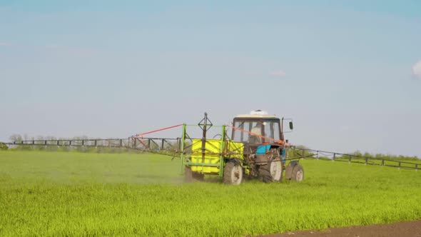 Farming Tractor Spraying on Field with Sprayer, Herbicides and Pesticides at Sunset. Farm Machinery