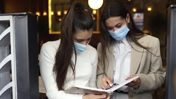 Two Businesswomen with Their Face Masks Debating Different Views on Work