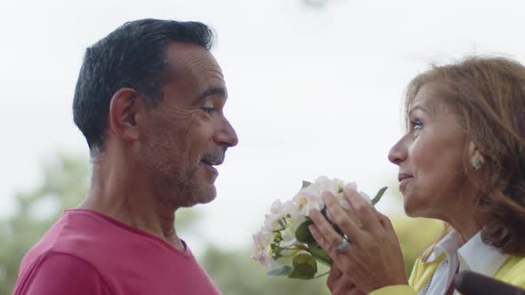 Closeup of Happy Senior Couple Sniffing Flowers and Talking