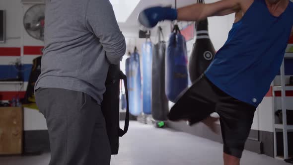 Caucasian man training with coach in boxing gym