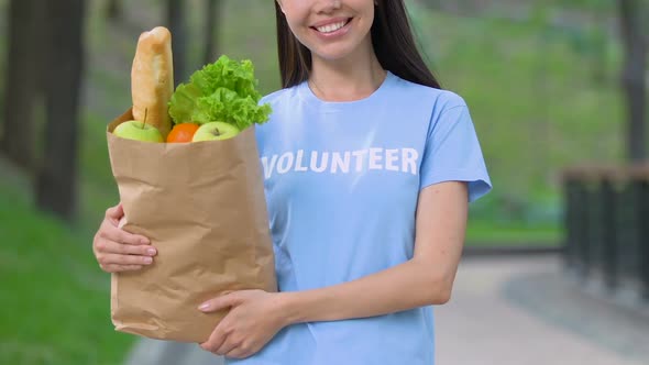 Volunteer With Food Package Smiling Outdoors, Donation for Starving People