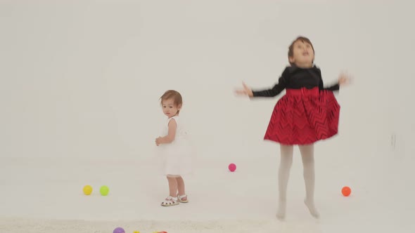 Toddler Girl Wearing Diaper and Her Sister Playing with Balls