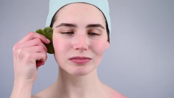 Closeup Portrait of a Young Woman Massaging Her Face with a Gouache Scraper