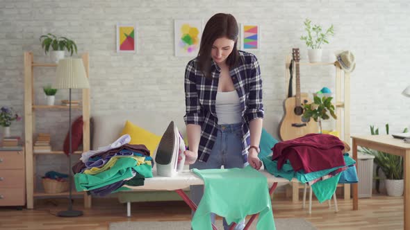 Cute Young Woman in Plaid Shirt Ironing Laundry Iron