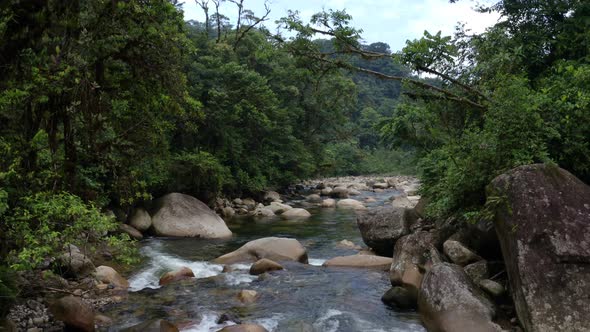 Flying over a tropical river alongside large boulders