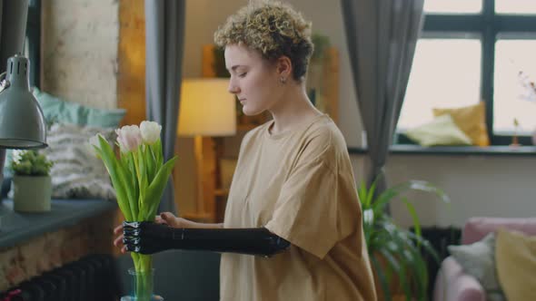 Girl with Prosthetic Arm Putting Flower Bouquet in Vase
