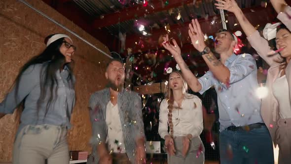 Happy Young People Are Dancing and Throwing Tinsel in Christmas Night Party