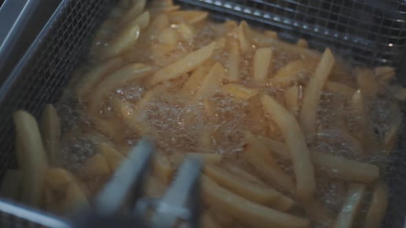 French Fries Fried in a Wire Basket in Hot Oil