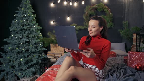 Happy woman with gadget on bed at Christmas. 