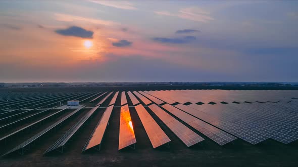 Timelapse Aerial Drone View Into Large Solar Panels at a Solar Farm at Early Spring Sunset