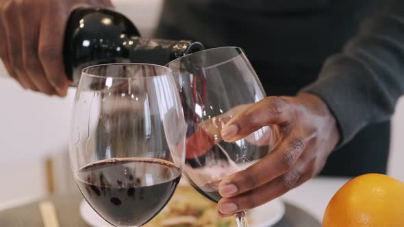 African American Man Pouring Wine Into Glasses for Romantic Dinner