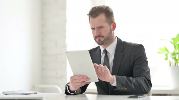 Young Businessman Reacting to Loss on Tablet in Office