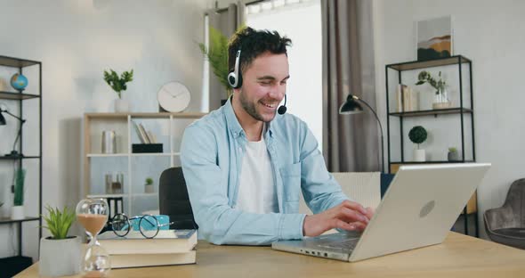 Young Man in Headset which Enjoying Video Chat with Friends on Laptop at Home in daytime