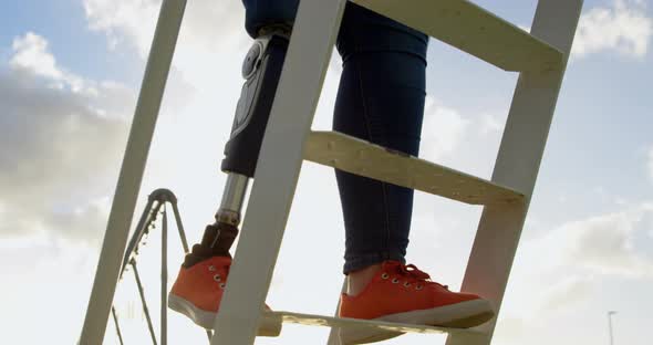 Low section of disabled woman climbing ladder in the park 4k