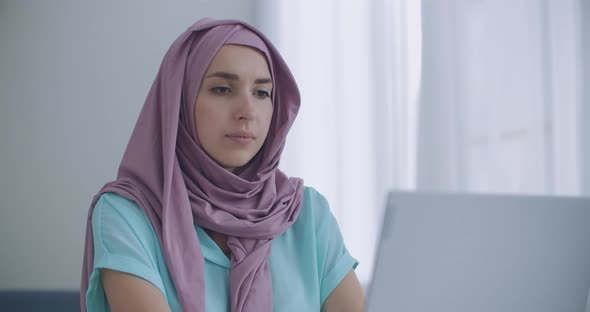 Beautiful Young Muslim Woman Is Working on Laptop on Her Workplace. A Young Muslim Woman, Sitting in
