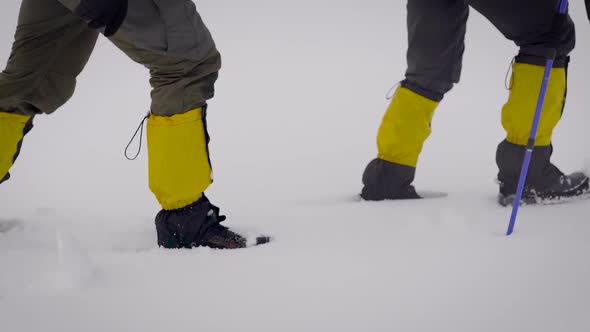 Two Men Went on an Expedition. Professional Trekking Boots and Leggings Help To Move in the Snow