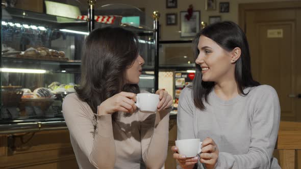 Two Happy Young Female Friends Smiling To the Camera at the Coffee Shop