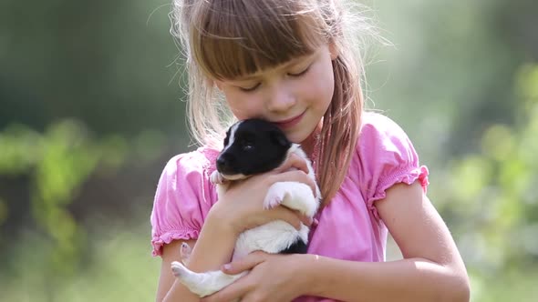 Pretty Child Girl Playing with Little Puppy Outdoors in Summer