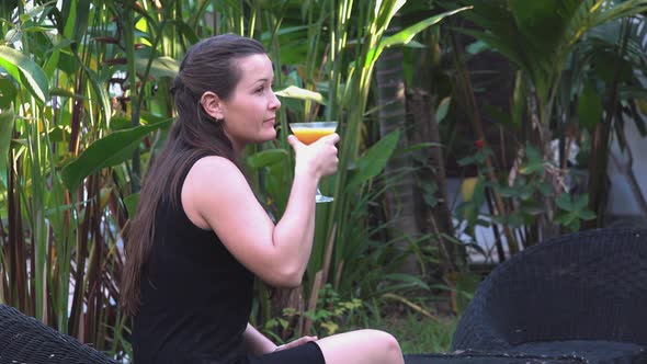 Medium Shot of a Beautiful Young Lady Enjoying a Cocktail in the Tropical Hotel Grounds