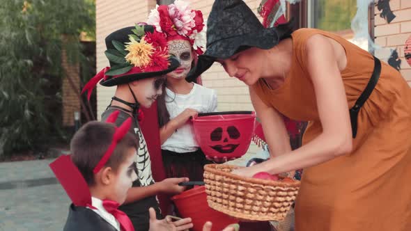 Adorable Children in Halloween Costumes Receiving Candy from Woman