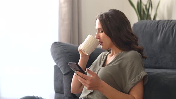 Young Woman Enjoys Morning Coffee and Chatting on the Smartphone