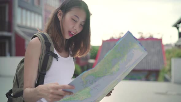 Young Asian backpacker woman direction and looking on location map while traveling at Chinatown.