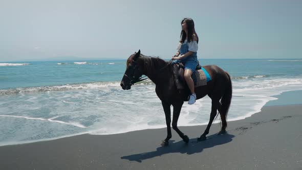 Cute Chinese Teenager Rides a Horse On The Beach In Bali