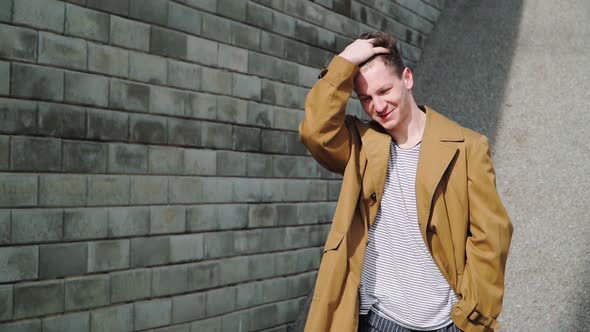 Stylish Happy Caucasian Guy Goes Along City Wall and Smiles