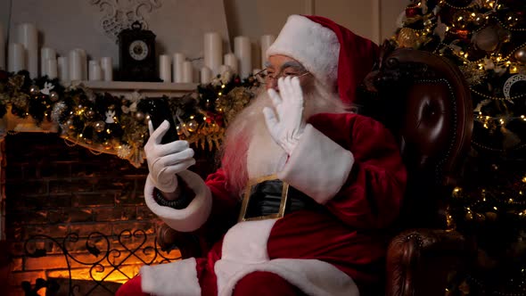 Modern Smiling Santa Claus Greets Talks to Children Online Smartphone Video Call