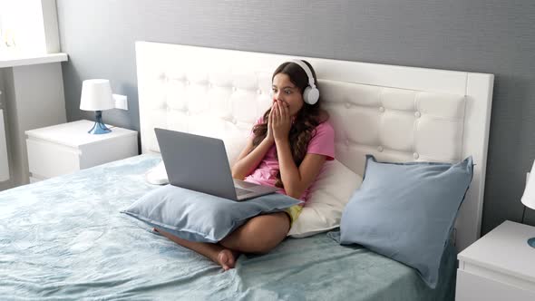 Happy Child in Headphones Laptop in Bed Having Amazed Face After Shocking News Education